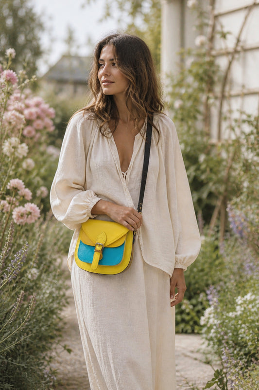 Handmade Leather Crossbody Bag - Romy in yellow and blue, surrounded by flowers and sketchbook.