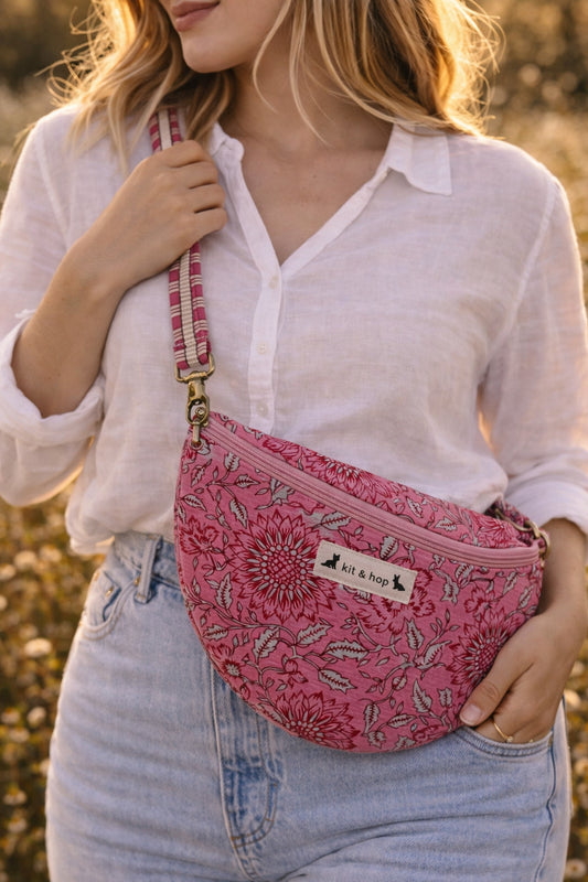 Handmade cross body bag Elara Wildflower Path in PINK FLORAL worn by woman in a field.