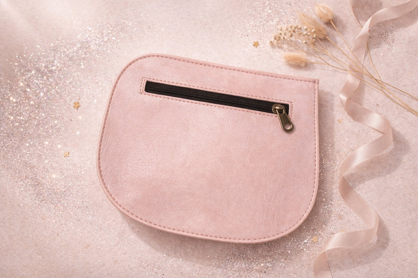 Handmade Leather Crossbody Bag - Romy - Petal resting on a sparkling surface with delicate flowers and ribbon.