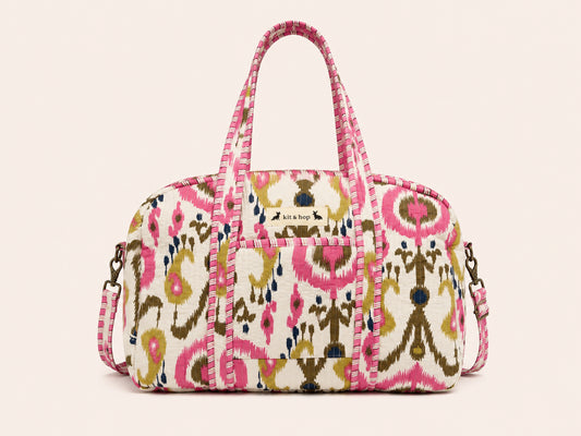 Handmade duffle bag hanging on a door, featuring a colorful pattern and practical design, perfect for travel and adventure.