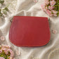 Handmade Leather Crossbody bag - Mira in black, pink, and red, surrounded by flowers on a linen background.