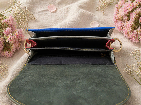 Handmade Leather Crossbody bag - Mira in black, pink, and red, surrounded by flowers on a linen background.