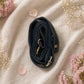Handmade Leather Crossbody bag - Mira in black, pink, and red, surrounded by flowers on a linen background.