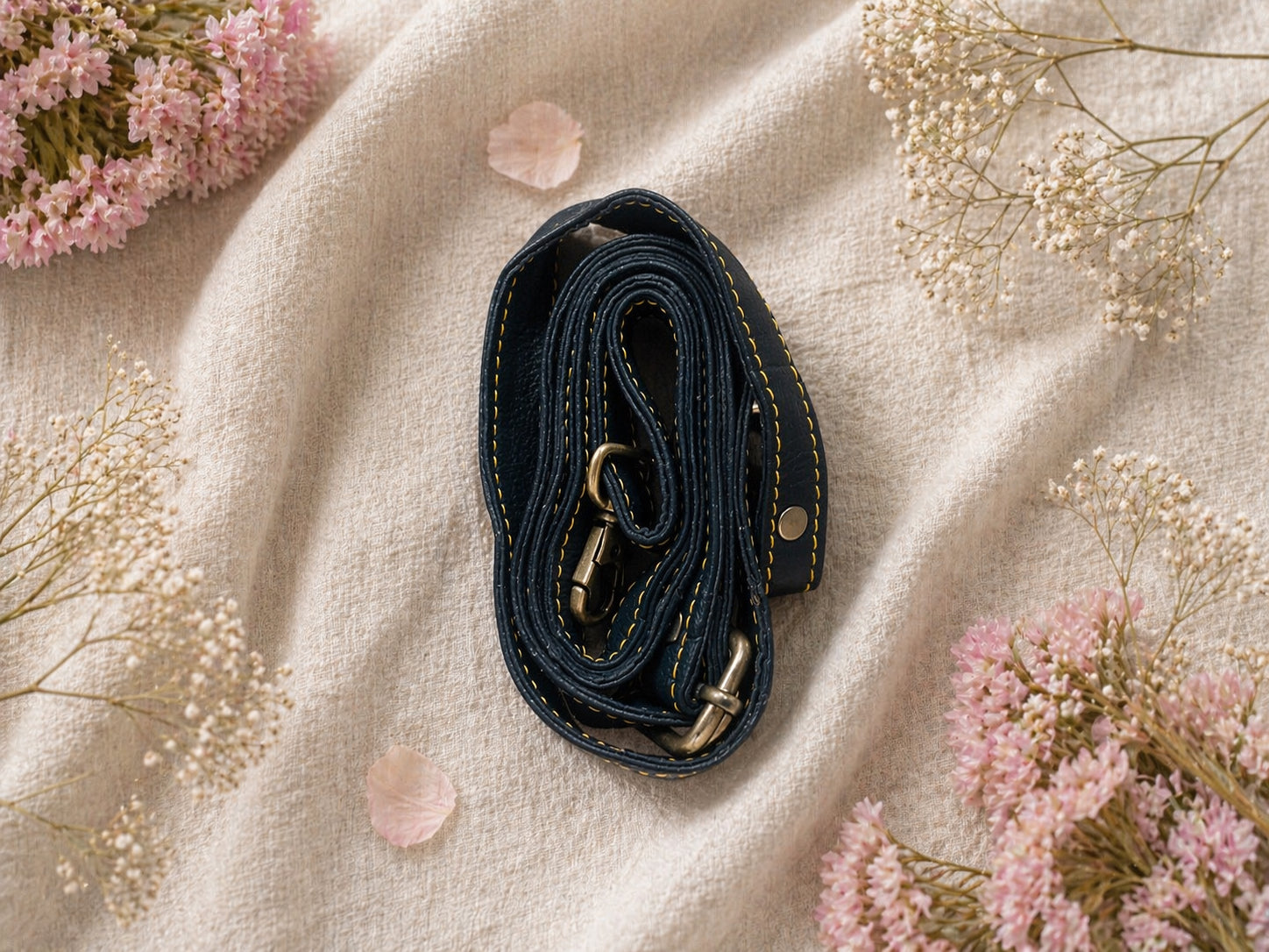 Handmade Leather Crossbody bag - Mira in black, pink, and red, surrounded by flowers on a linen background.