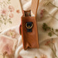 A Handmade Leather Crossbody Bag with vibrant colors, featuring an orange, green, and purple design, surrounded by floral accents.