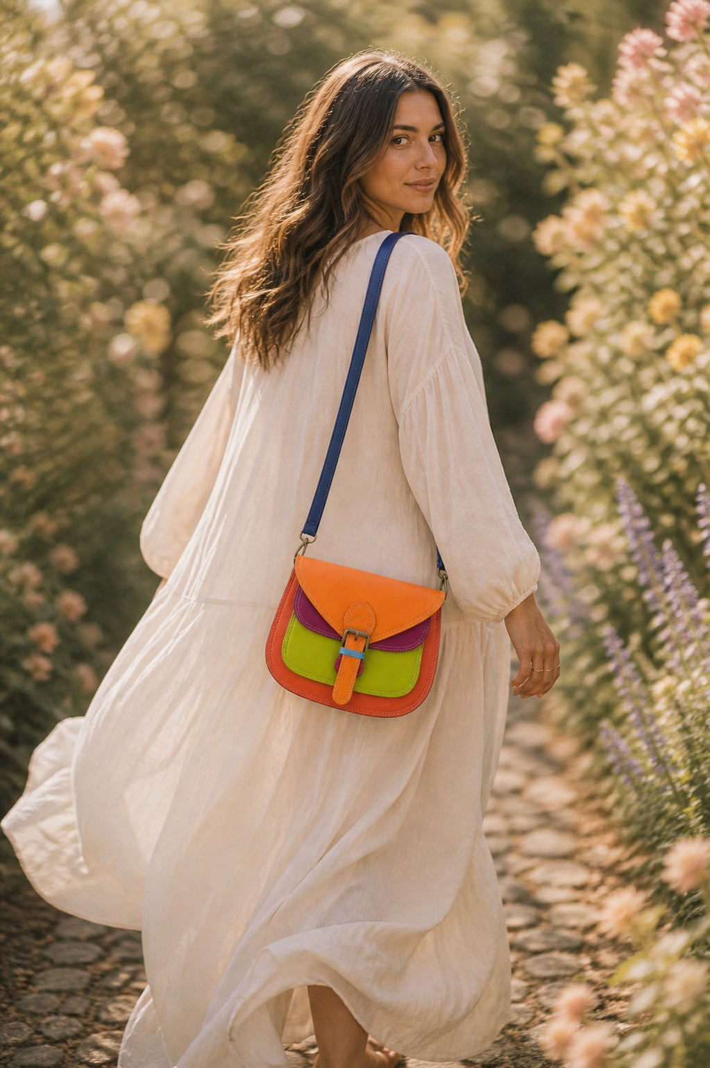 A Handmade Leather Crossbody Bag with vibrant colors, featuring an orange, green, and purple design, surrounded by floral accents.