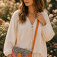 Handmade Leather Crossbody Bag - Romy in a model's hands, showcasing its unique design and vibrant colors against a floral backdrop.