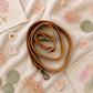 Handmade Leather Crossbody Bag - Romy in a model's hands, showcasing its unique design and vibrant colors against a floral backdrop.