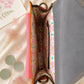 Handmade Leather Crossbody Bag - Romy in a model's hands, showcasing its unique design and vibrant colors against a floral backdrop.