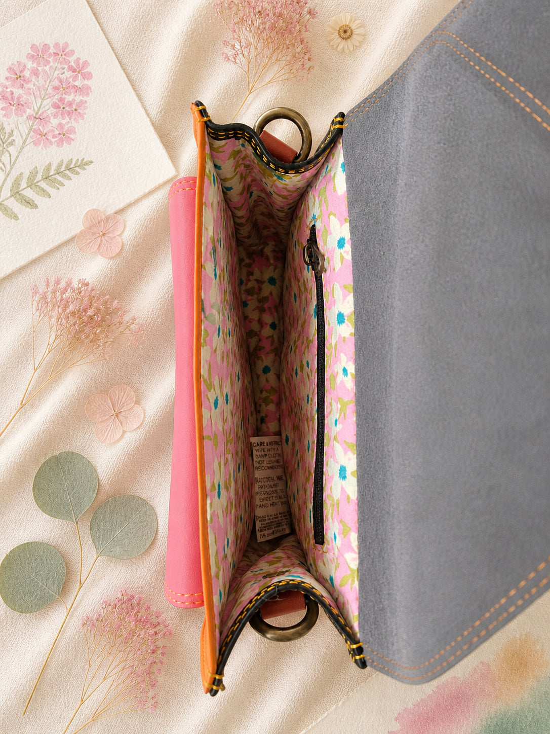 Handmade Leather Crossbody Bag - Romy in a model's hands, showcasing its unique design and vibrant colors against a floral backdrop.
