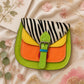 Handmade Leather Crossbody Bag with vibrant colors and zebra print flap on a floral background.