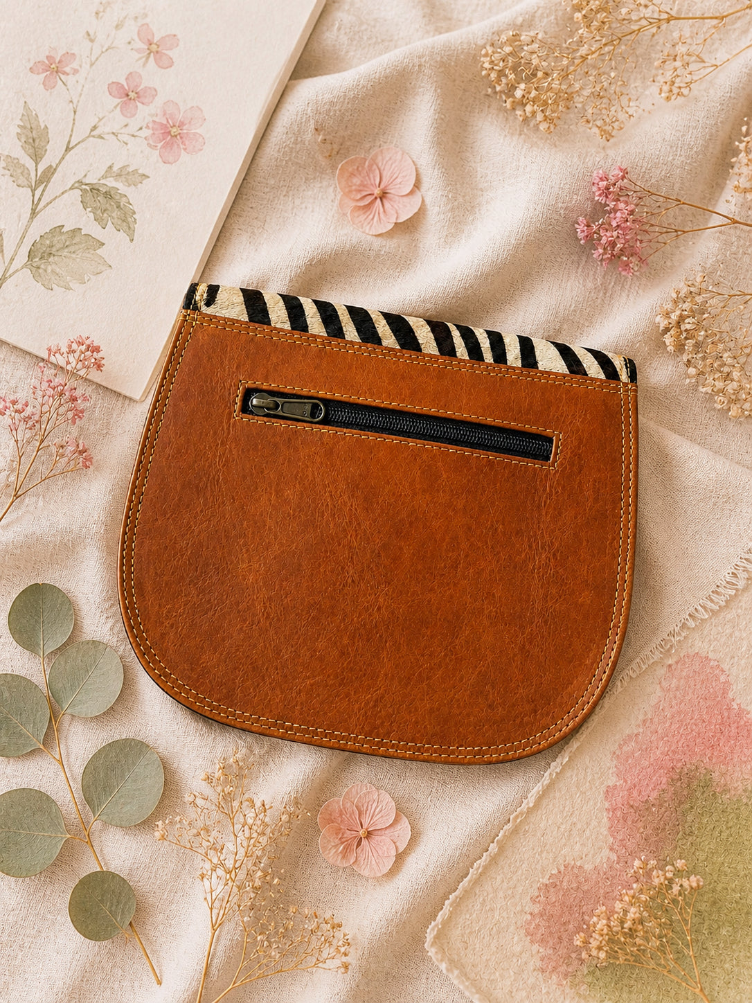 Handmade Leather Crossbody Bag with vibrant colors and zebra print flap on a floral background.
