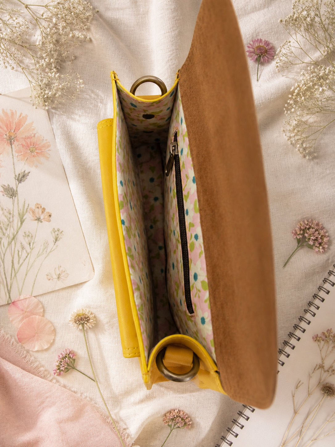 Handmade Leather Crossbody Bag - Romy in yellow and blue, surrounded by flowers and sketchbook.