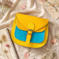 Handmade Leather Crossbody Bag - Romy in yellow and blue, surrounded by flowers and sketchbook.