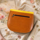 Handmade Leather Crossbody Bag - Romy in yellow and blue, surrounded by flowers and sketchbook.