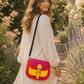 Handmade Leather Crossbody Bag in vibrant red and yellow with floral background.
