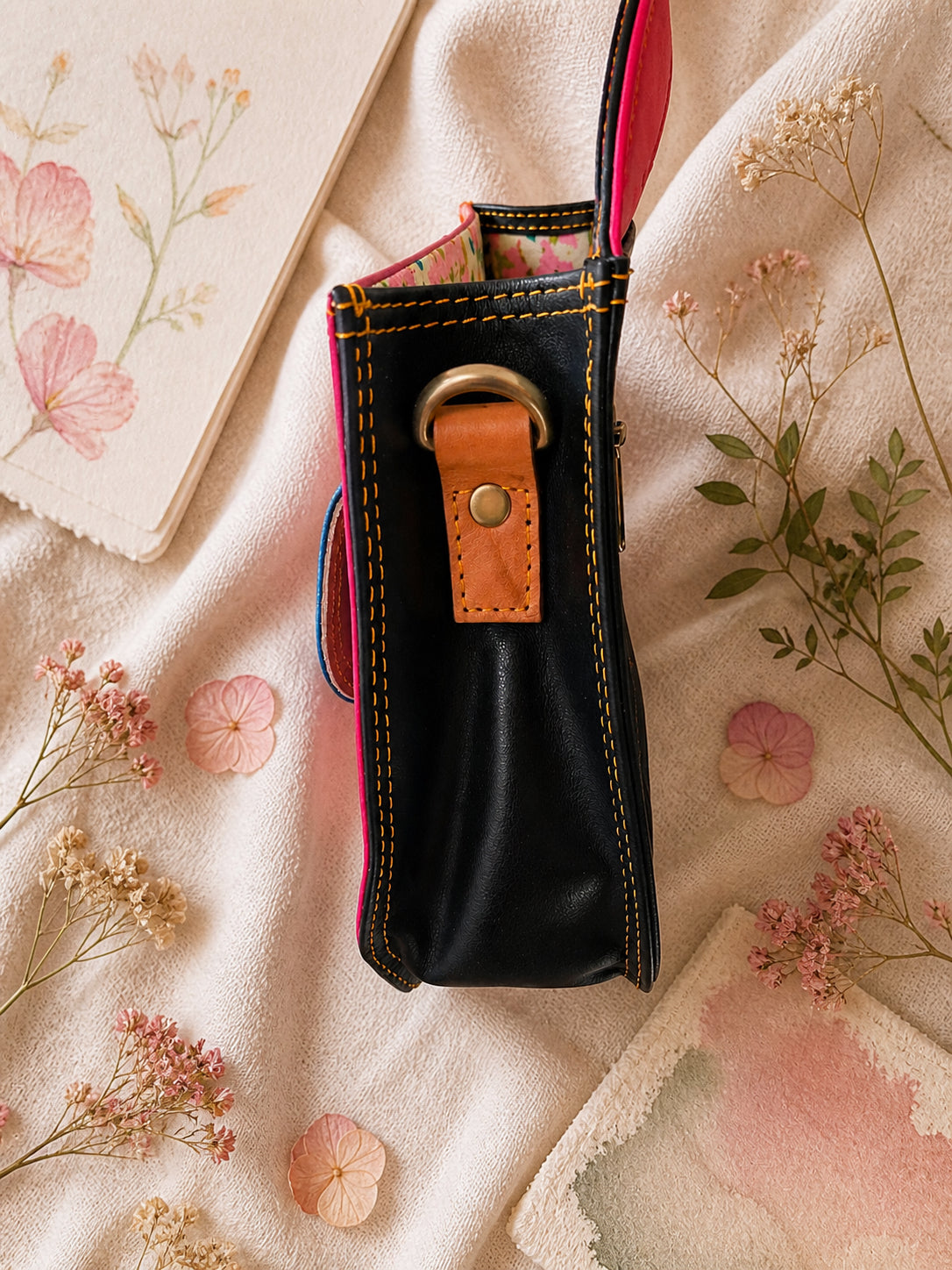 Handmade Leather Crossbody Bag in vibrant fuchsia, blue, and red colors, featuring a stylish buckle detail on a floral background.