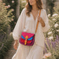 Handmade Leather Crossbody Bag in vibrant fuchsia, blue, and red colors, featuring a stylish buckle detail on a floral background.