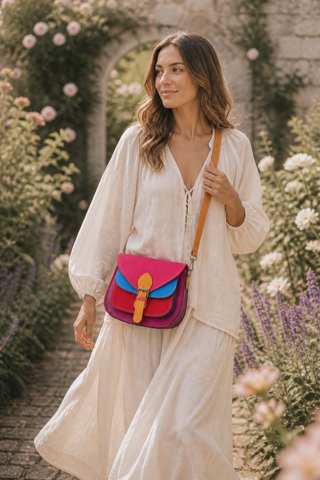 Handmade Leather Crossbody Bag in vibrant fuchsia, blue, and red colors, featuring a stylish buckle detail on a floral background.