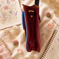Handmade Leather Crossbody Bag in vibrant colors with pink, blue, and yellow hues, resting on a soft fabric backdrop.
