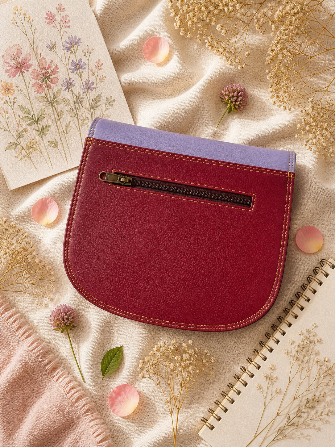 Handmade Leather Crossbody Bag in vibrant colors with pink, blue, and yellow hues, resting on a soft fabric backdrop.