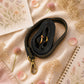 Handmade Leather Crossbody Bag in vibrant colors with pink, blue, and yellow hues, resting on a soft fabric backdrop.