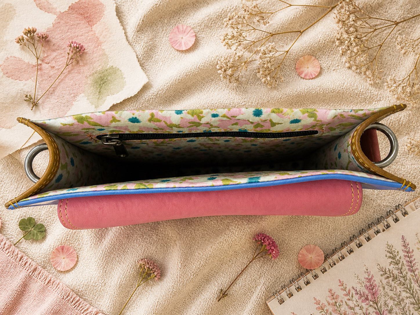 Handmade Leather Crossbody Bag - Romy - Painted Garden - Stardust displayed on a soft fabric with flowers and sketches.