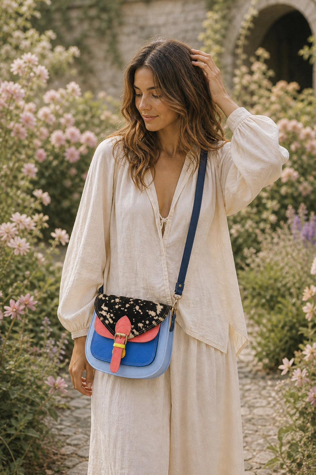 Handmade Leather Crossbody Bag - Romy - Painted Garden - Stardust displayed on a soft fabric with flowers and sketches.