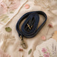 Handmade Leather Crossbody Bag - Romy - Painted Garden - Stardust displayed on a soft fabric with flowers and sketches.