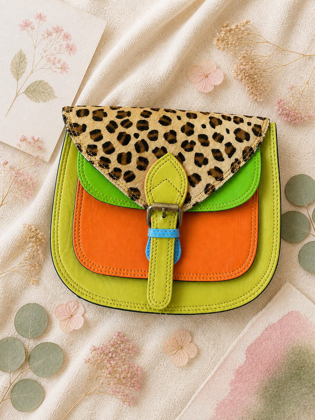 Handmade Leather Crossbody Bag in vibrant colors with leopard print flap on a textured background.