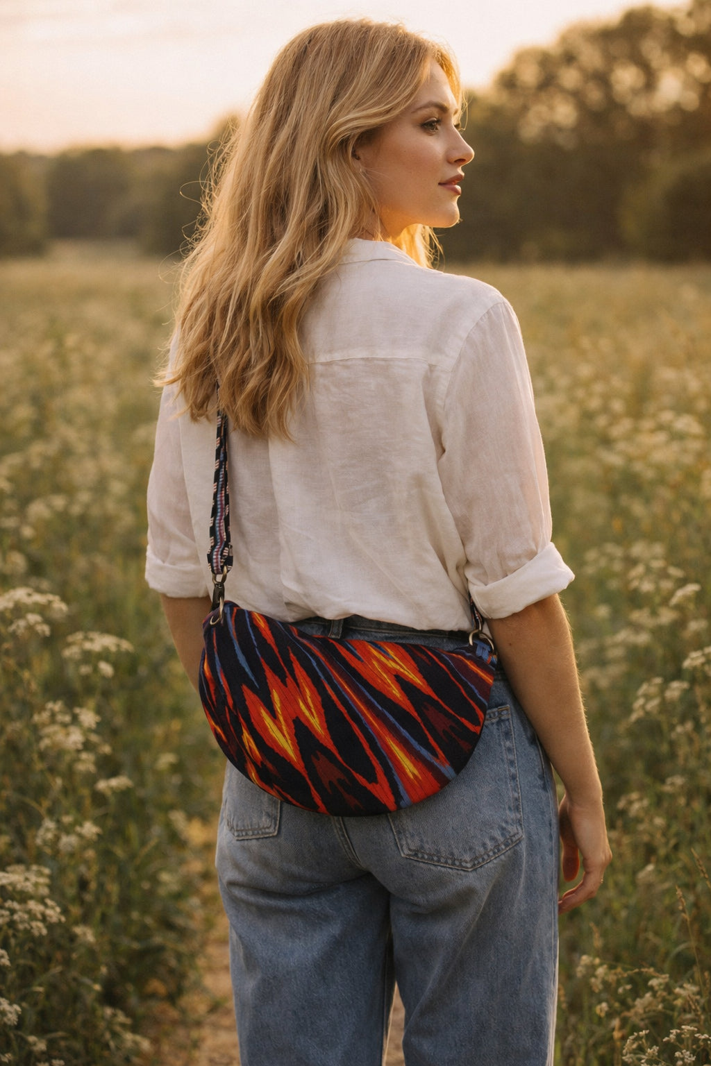 Handmade cross body bag in vibrant colors worn by a woman in a field, showcasing style and comfort.
