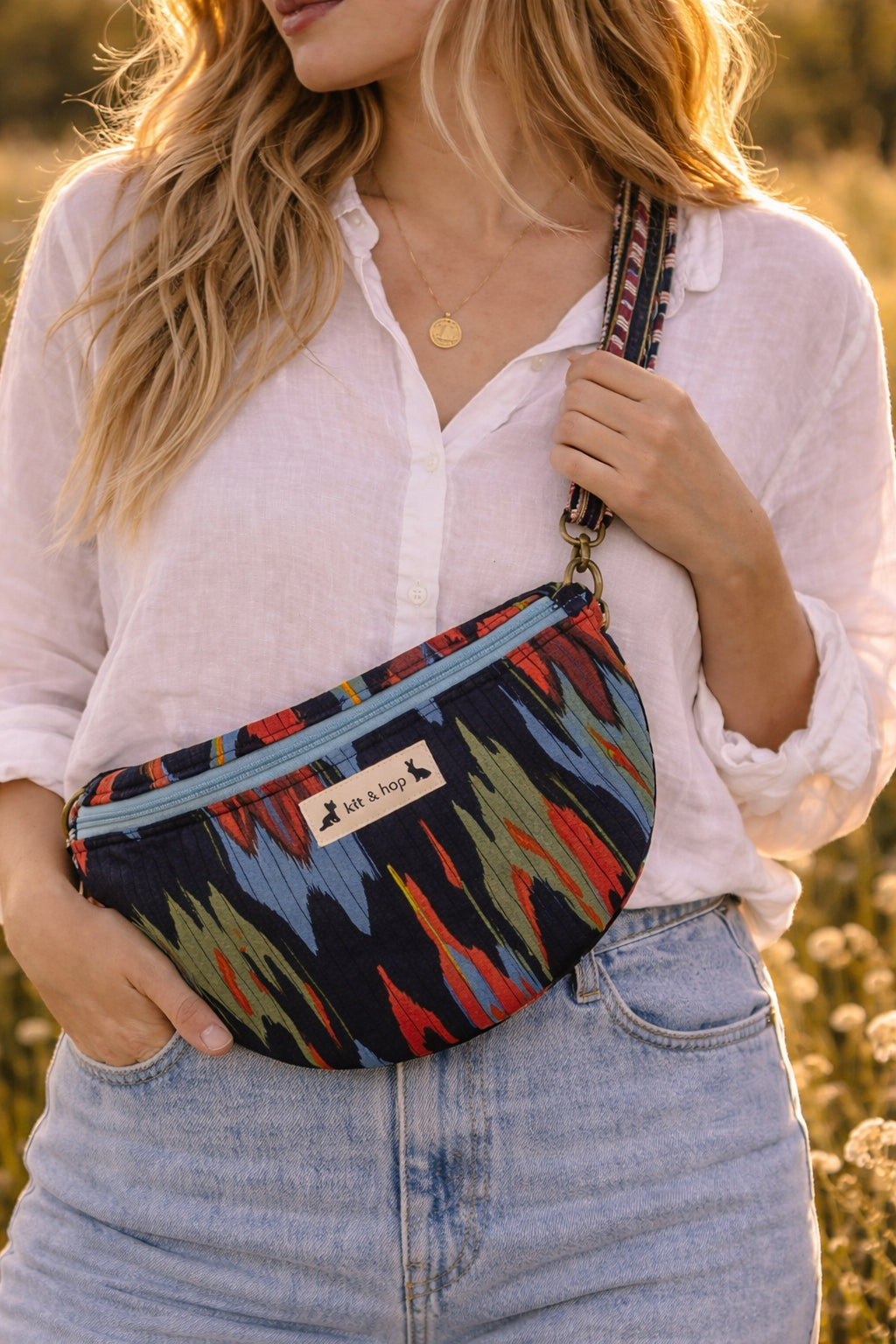 Handmade cross body bag in vibrant colors worn by a woman in a field, showcasing style and comfort.