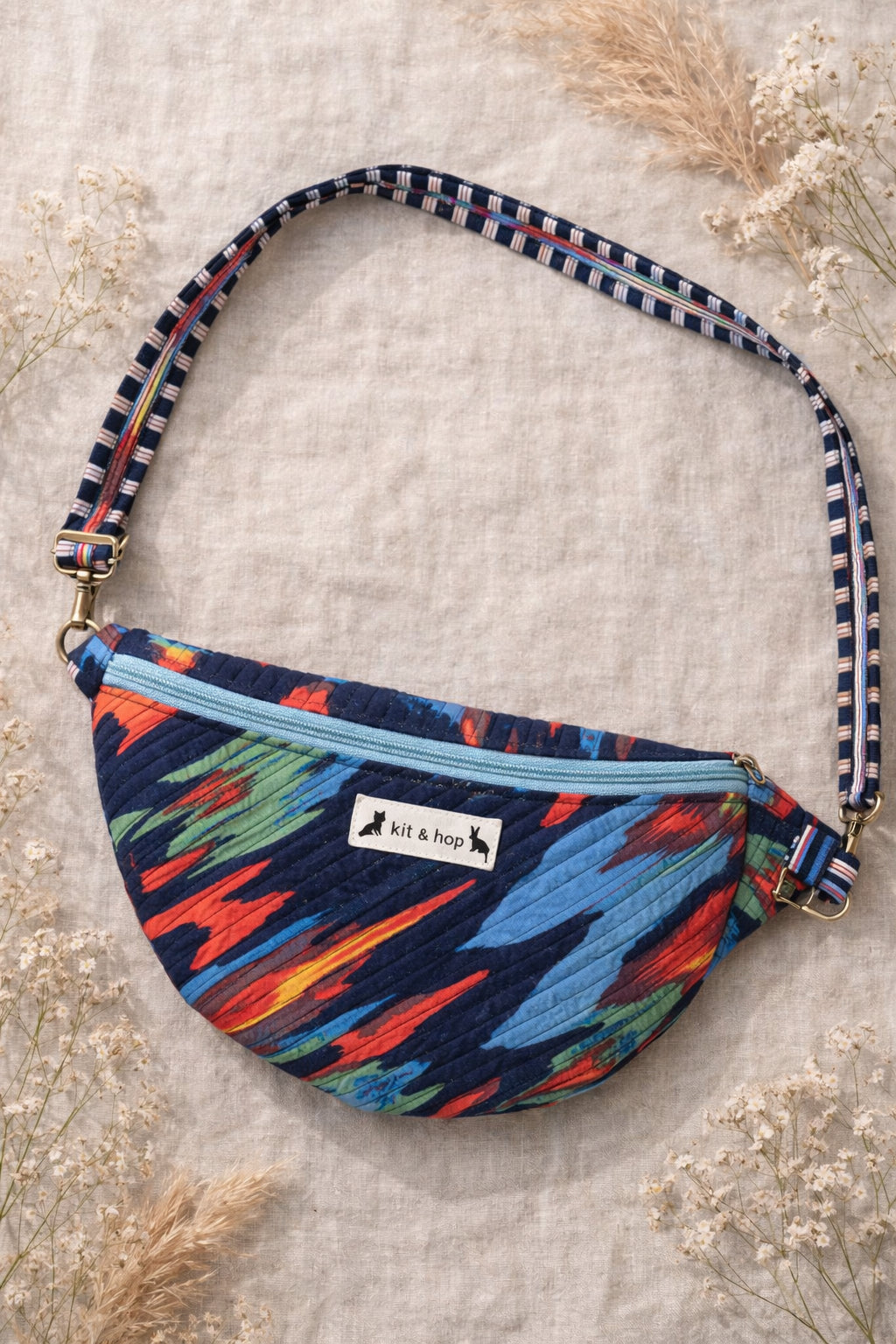 Handmade cross body bag in vibrant colors worn by a woman in a field, showcasing style and comfort.