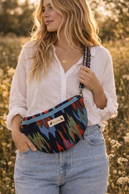 Handmade cross body bag in vibrant colors worn by a woman in a field, showcasing style and comfort.
