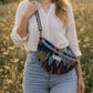 Handmade cross body bag in vibrant colors worn by a woman in a field, showcasing style and comfort.