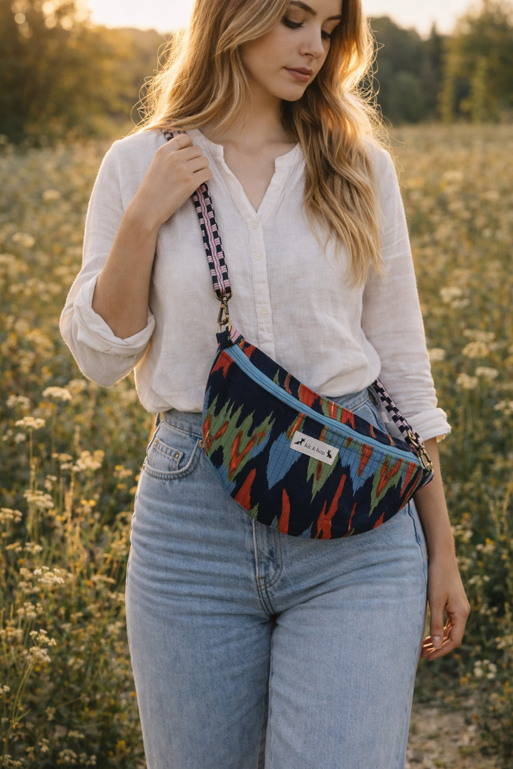 Handmade cross body bag in vibrant colors worn by a woman in a field, showcasing style and comfort.