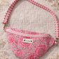 Handmade cross body bag Elara Wildflower Path in PINK FLORAL worn by woman in a field.