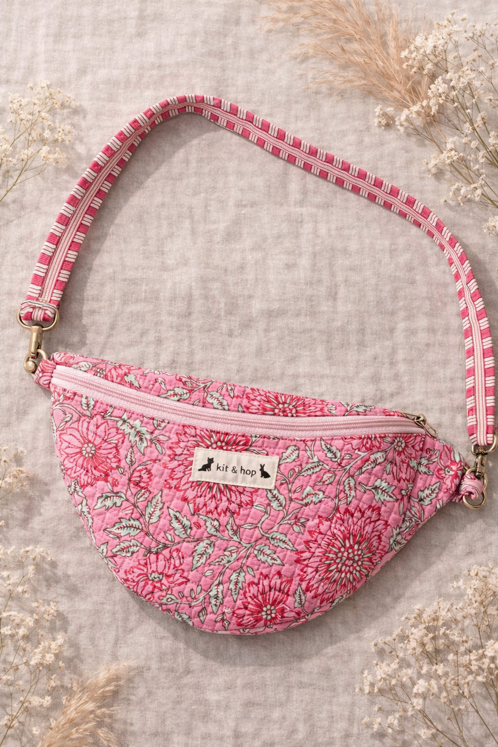 Handmade cross body bag Elara Wildflower Path in PINK FLORAL worn by woman in a field.