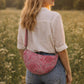 Handmade cross body bag Elara Wildflower Path in PINK FLORAL worn by woman in a field.