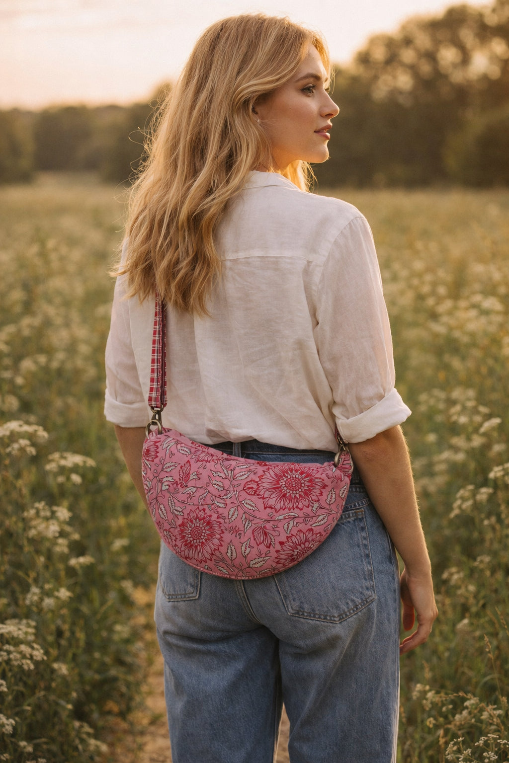 Handmade cross body bag Elara Wildflower Path in PINK FLORAL worn by woman in a field.