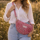Handmade cross body bag Elara Wildflower Path in PINK FLORAL worn by woman in a field.