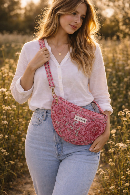Handmade cross body bag Elara Wildflower Path in PINK FLORAL worn by woman in a field.