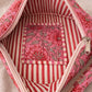 Handmade cross body bag Elara Wildflower Path in PINK FLORAL worn by woman in a field.