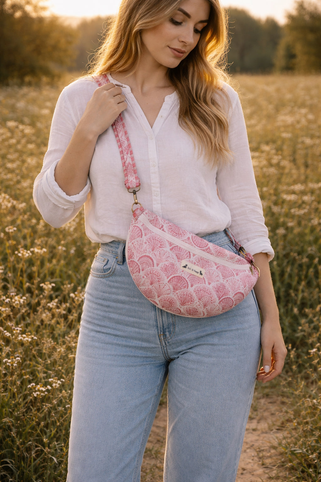 A model wearing the Handmade cross body bag in a wildflower field, showcasing its soft design and adjustable strap.