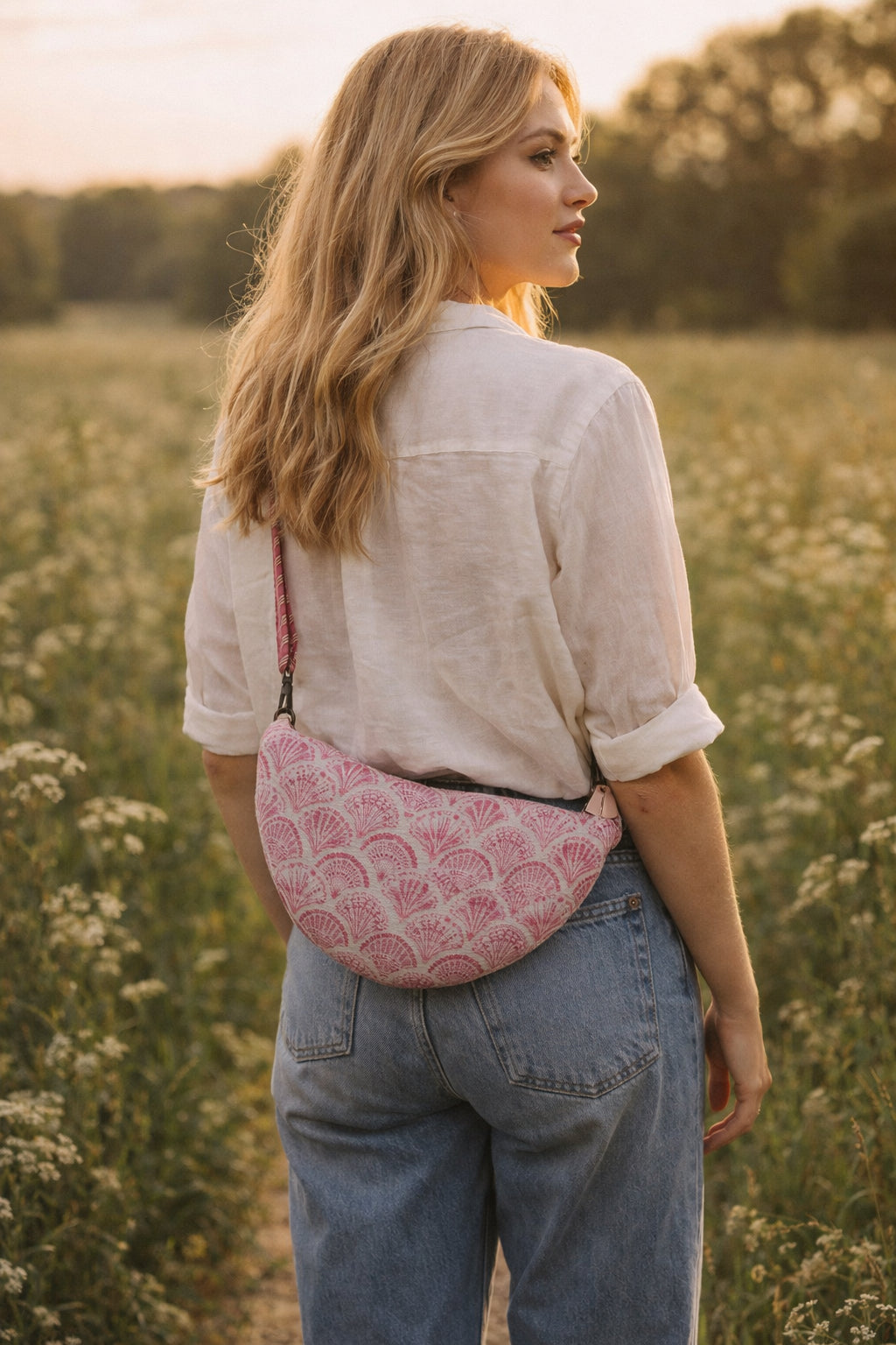 A model wearing the Handmade cross body bag in a wildflower field, showcasing its soft design and adjustable strap.