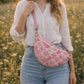 A model wearing the Handmade cross body bag in a wildflower field, showcasing its soft design and adjustable strap.