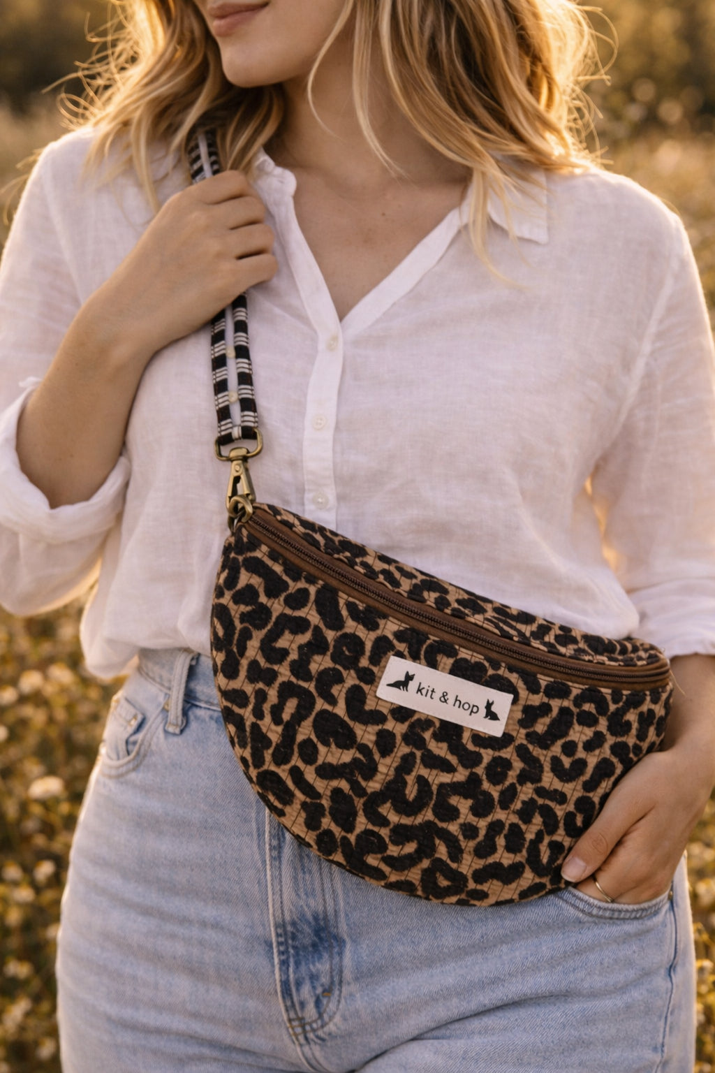 Handmade cross body bag Elara Wildflower Path in LEOPARD PRINT worn by woman in a field.
