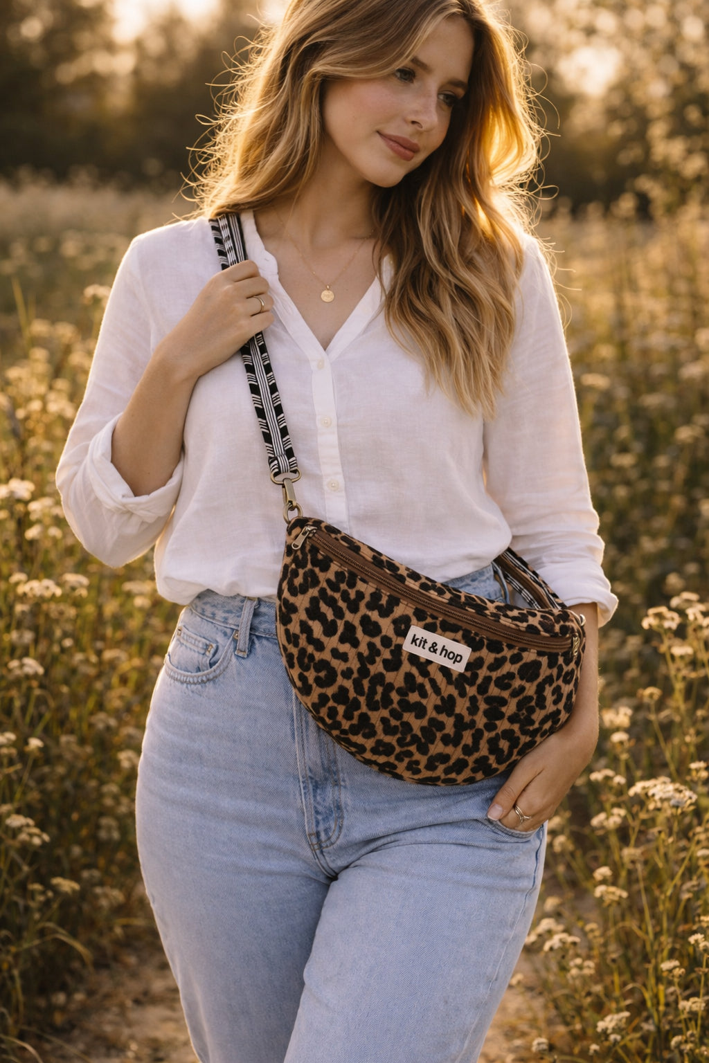 Handmade cross body bag Elara Wildflower Path in LEOPARD PRINT worn by woman in a field.