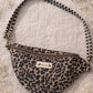 Handmade cross body bag Elara Wildflower Path in LEOPARD PRINT worn by woman in a field.