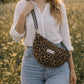 Handmade cross body bag Elara Wildflower Path in LEOPARD PRINT worn by woman in a field.